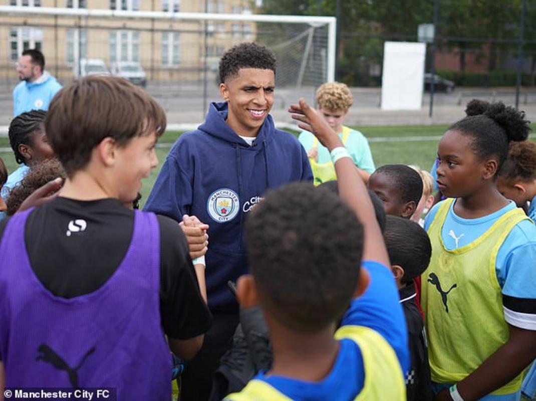 Cầu thủ 20 tuổi bị vây quanh bởi những đứa trẻ háo hức và vui vẻ tại trường trung học Trinity